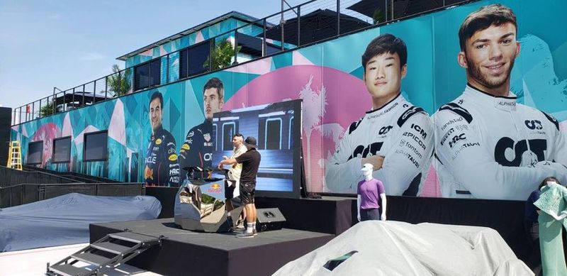 Large printed Formula 1 driver portraits wrapping a trackside building at the Miami Grand Prix