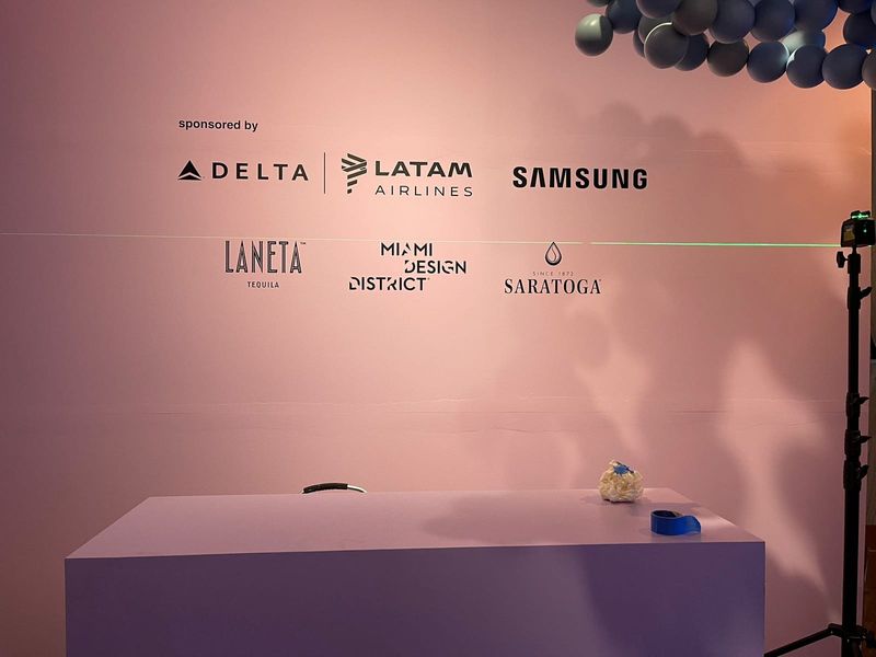 Printed event sponsor wall carrying Delta, LATAM Airlines, Samsung, Laneta Tequila, Miami Design District and Saratoga logos