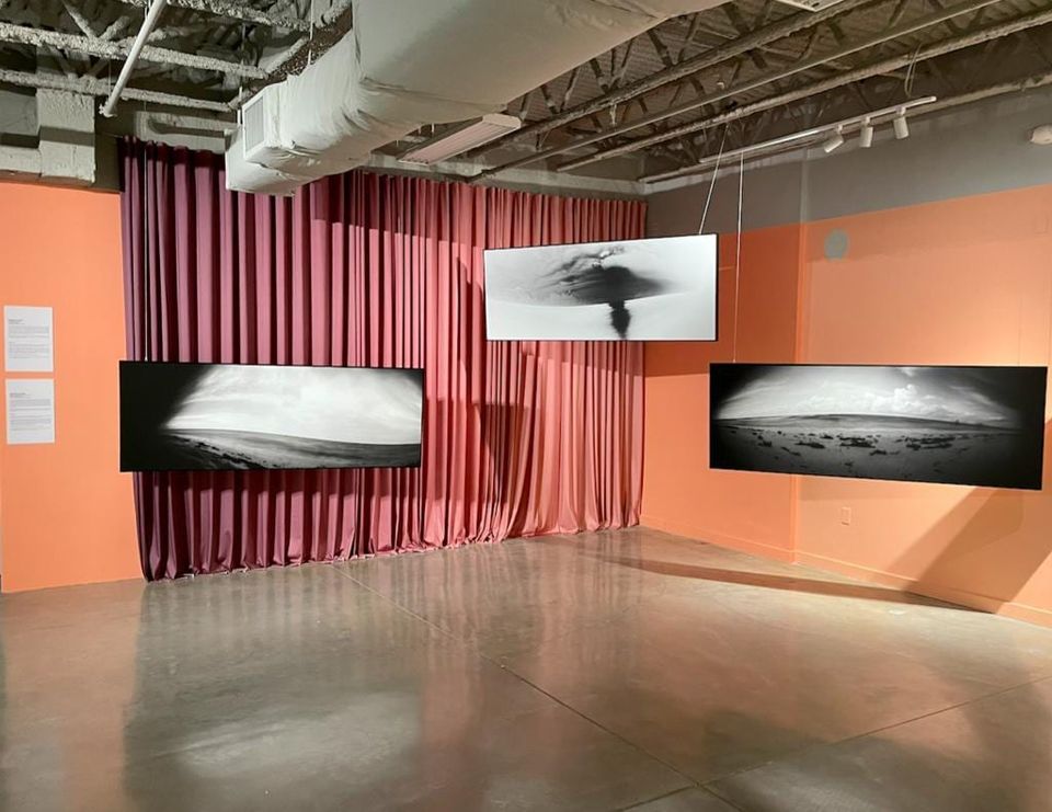 Art fair booth built with draped fabric walls, hung with large-format photographic prints