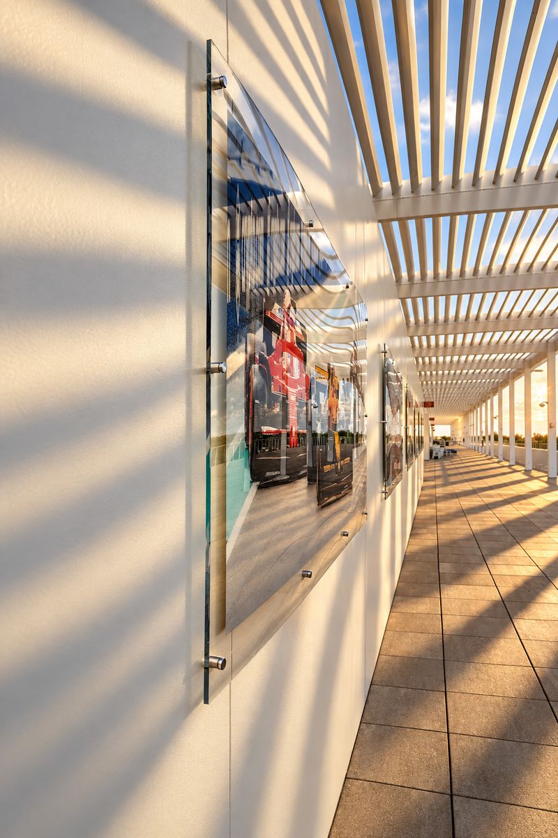 Row of large acrylic-mounted photo prints along an open-air stadium terrace hallway