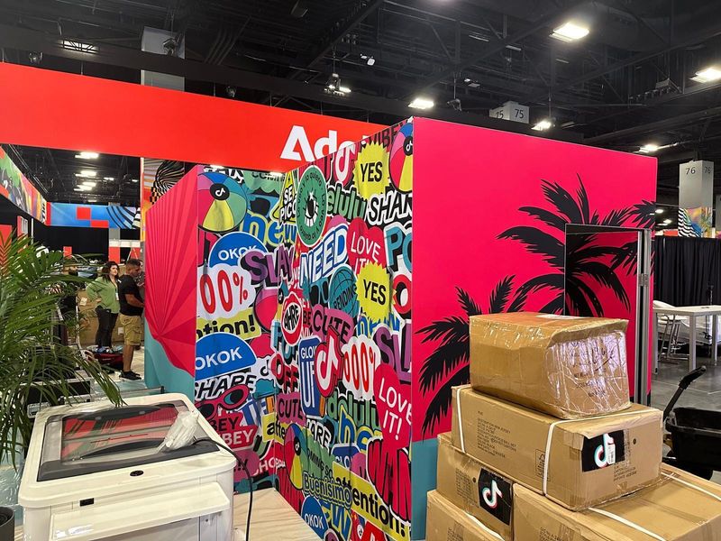 TikTok-branded exhibit walls with colorful typographic graphics and pink palm-tree panels during booth installation