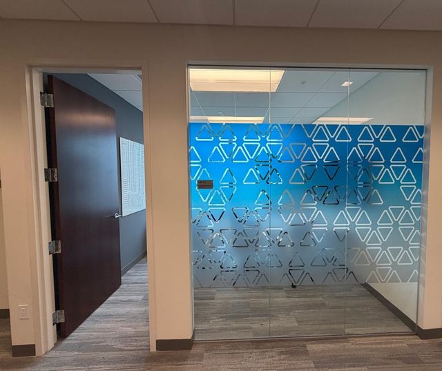 Glass meeting room front with a blue gradient window film cut in a pattern of triangles, fading to frosted toward the floor
